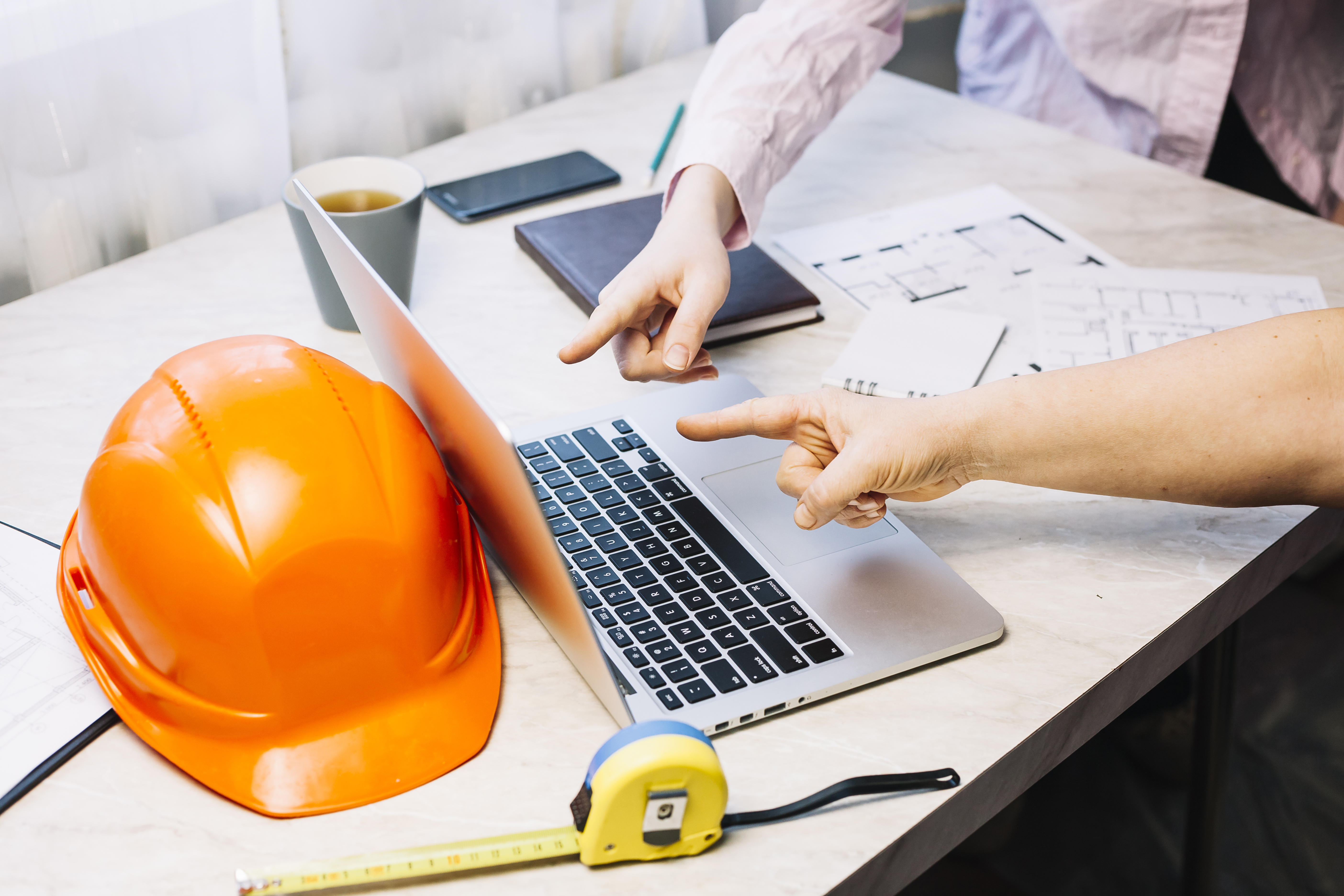 pointing at a laptop with hardhat behind