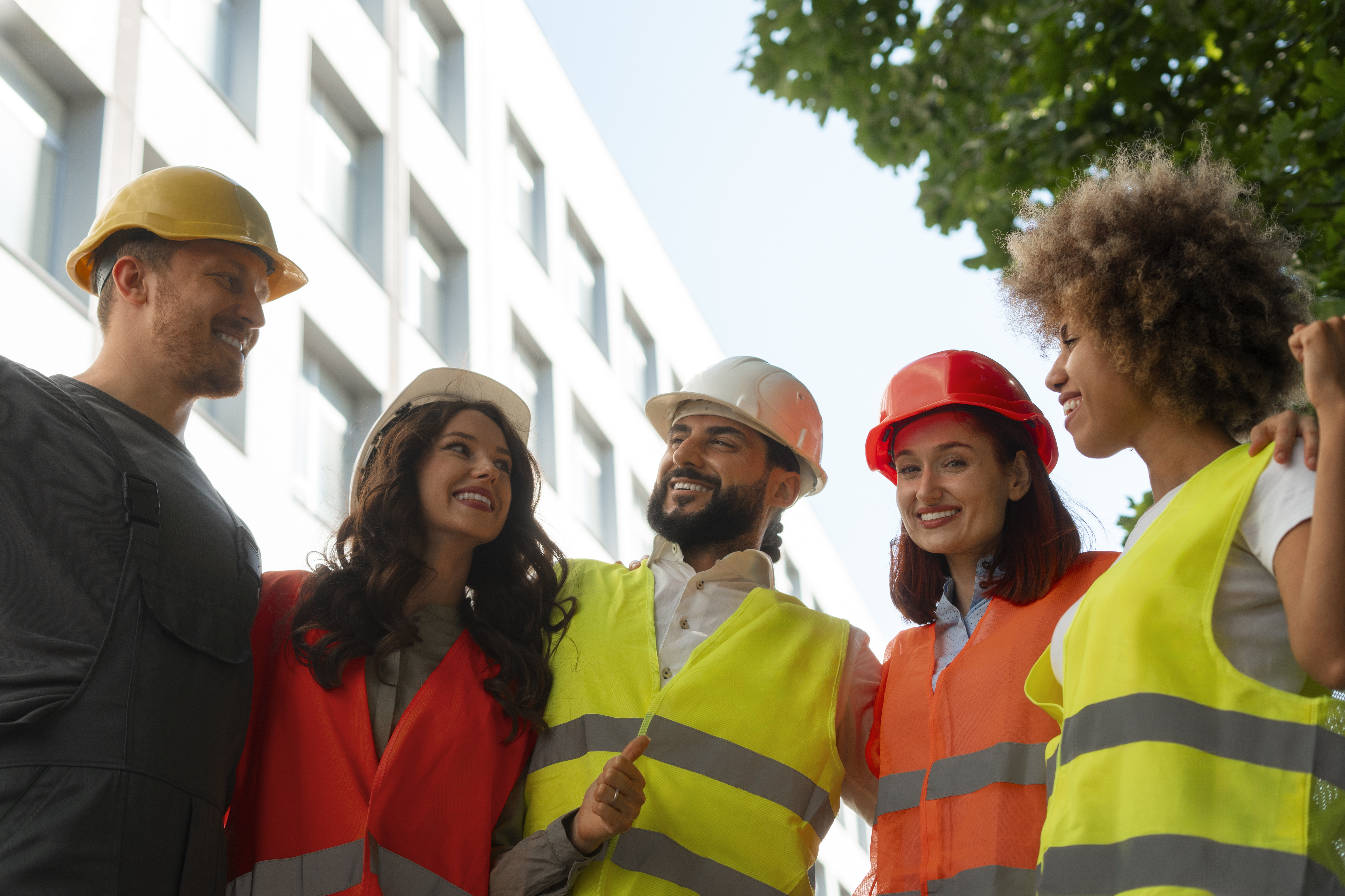 Group of workers in hard hats and hi vis, smiling together.